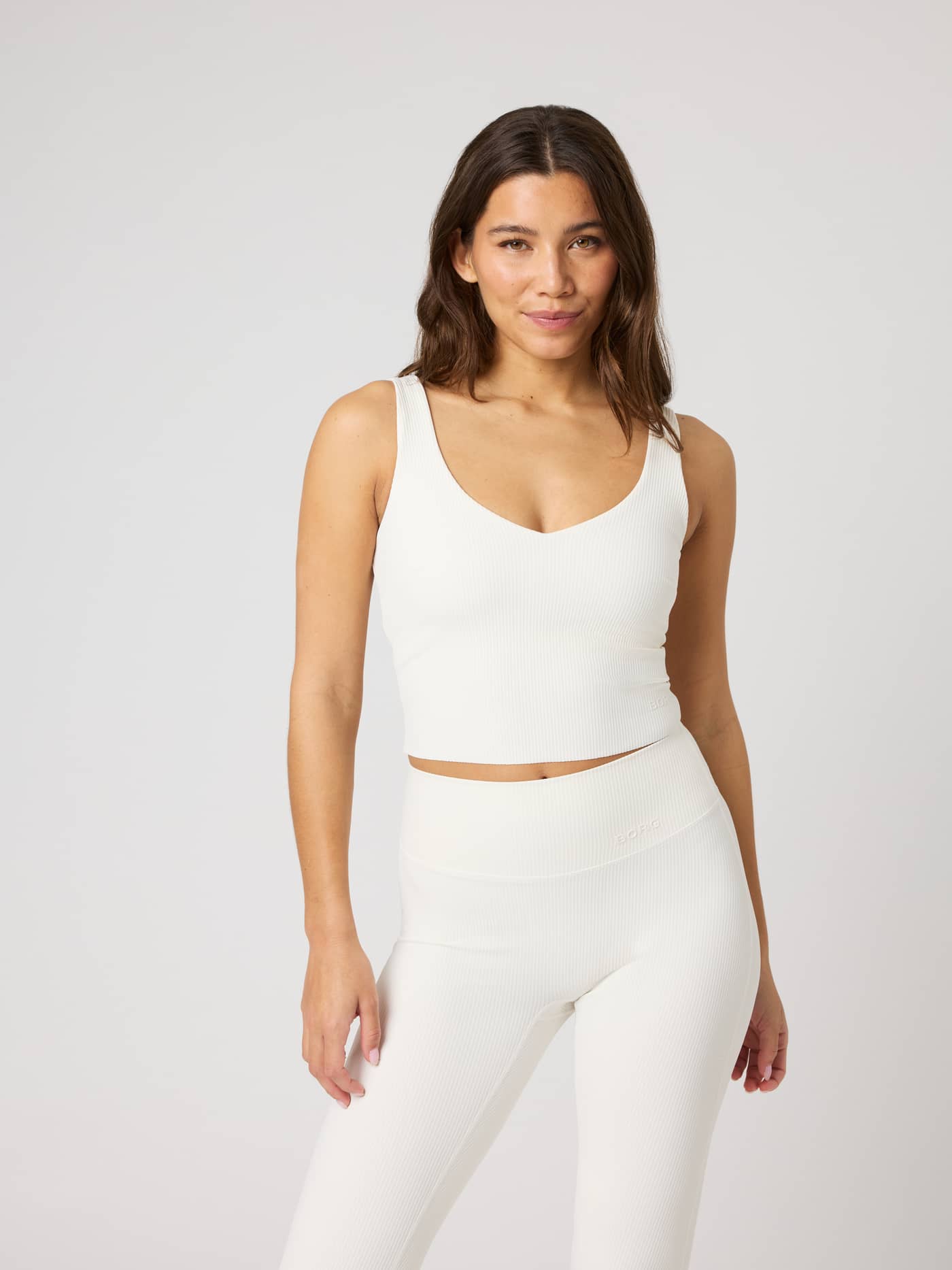 Vooraanzicht van de Studio Ribbed V-Neck Top in Tofu (Wit), een nauwsluitende cropped trainingstop met ribtextuur. - Image 1