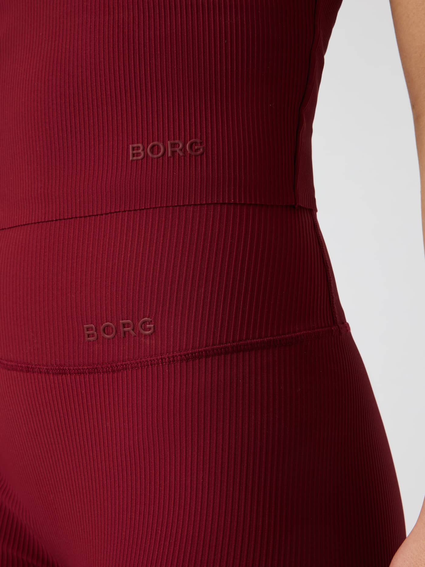 Närbild på Studio Ribbed V-Neck Top i Cabernet (röd) med BORG-logotyp och ribbad textur. - Image 4