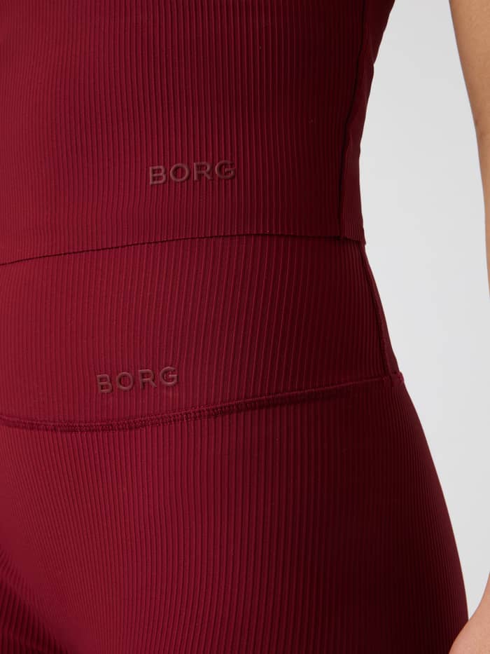 Close-up of the Studio Ribbed V-Neck Top in Cabernet (Red) featuring the BORG logo and ribbed texture.