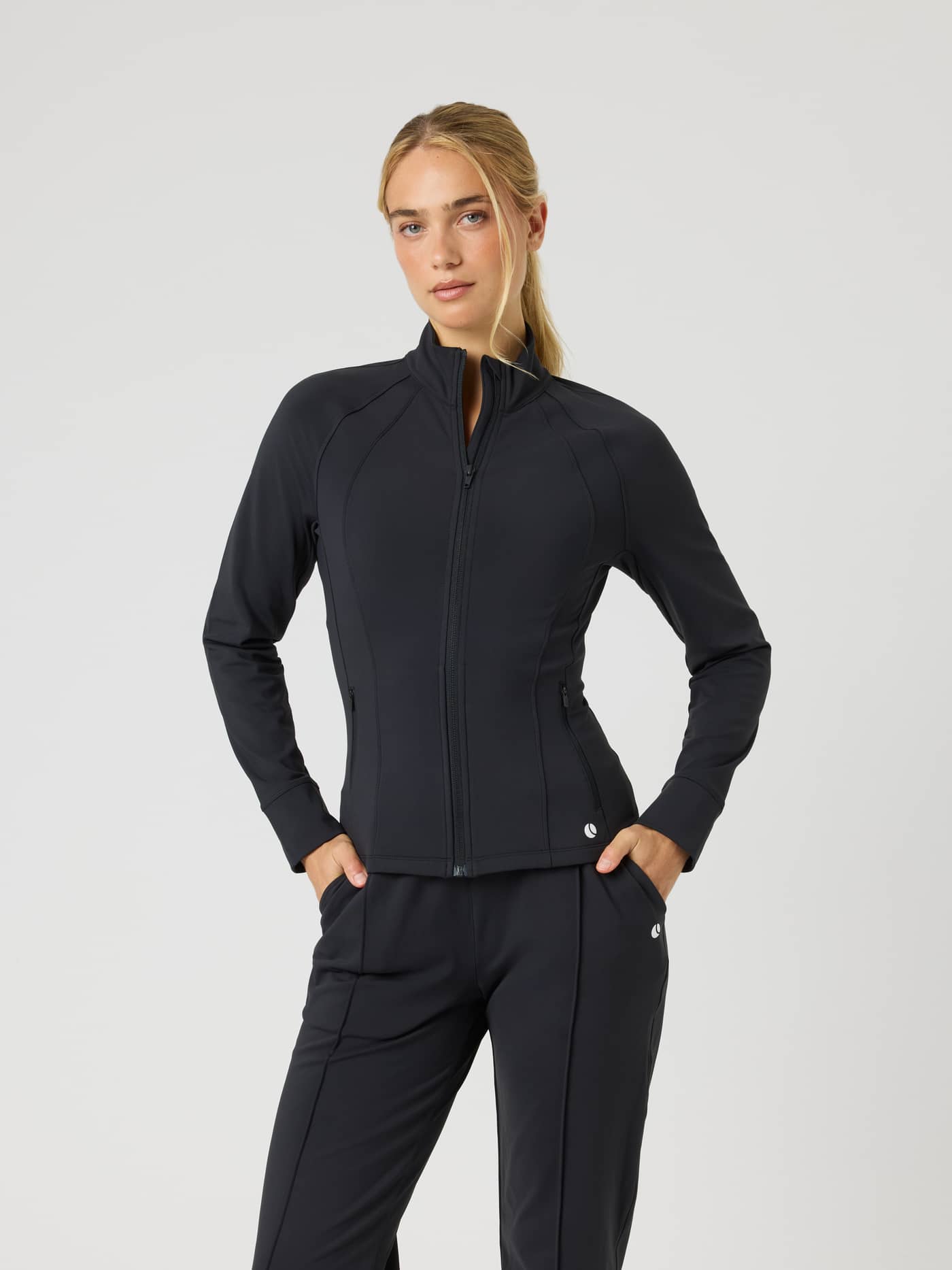 Ace Track Jacket i Black Beauty (Sort) set forfra på en kvinde til tennis og bevægelse. - Image 1