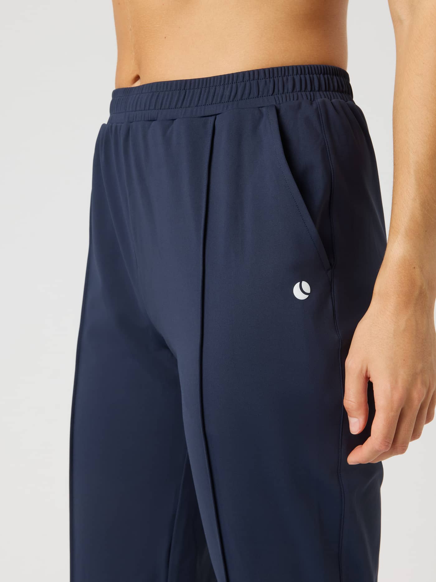 Close-up of the Ace Track Pants in Night Sky (Navy) for tennis, featuring a side pocket and small white logo. - Image 4