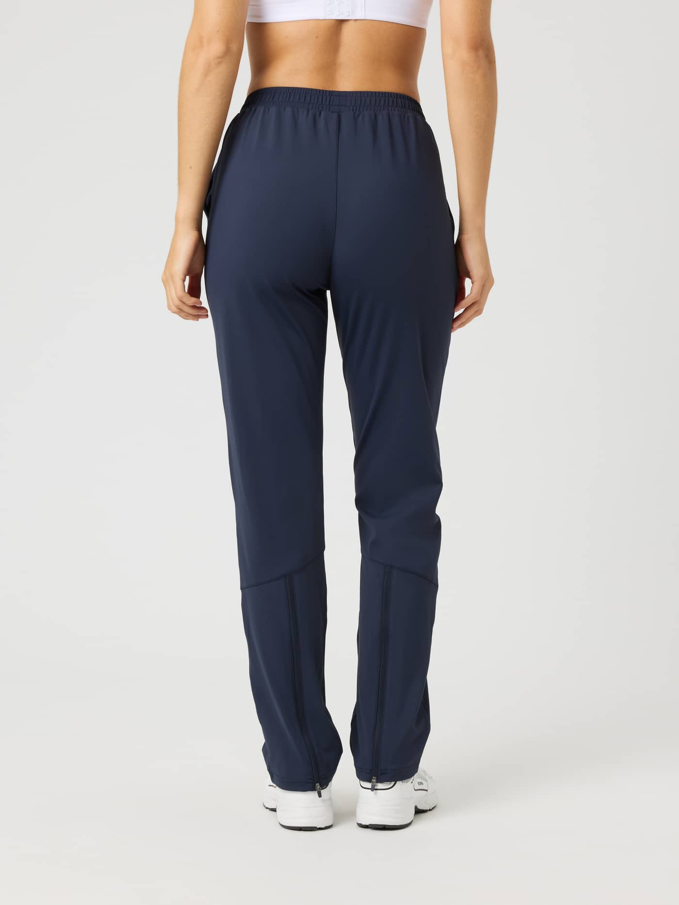 Back view of a woman wearing Ace Track Pants in Night Sky (Navy) for tennis, with a regular fit and zipped leg openings. - Image 2