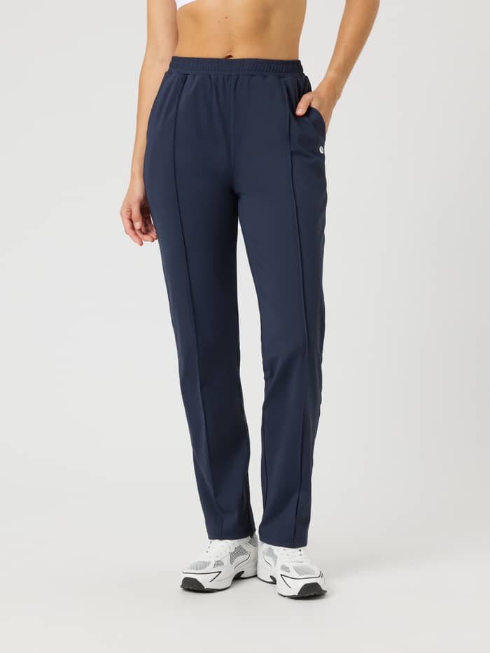 Front view of a model wearing Ace Track Pants in Night sky (Navy) with a white logo for tennis and padel.