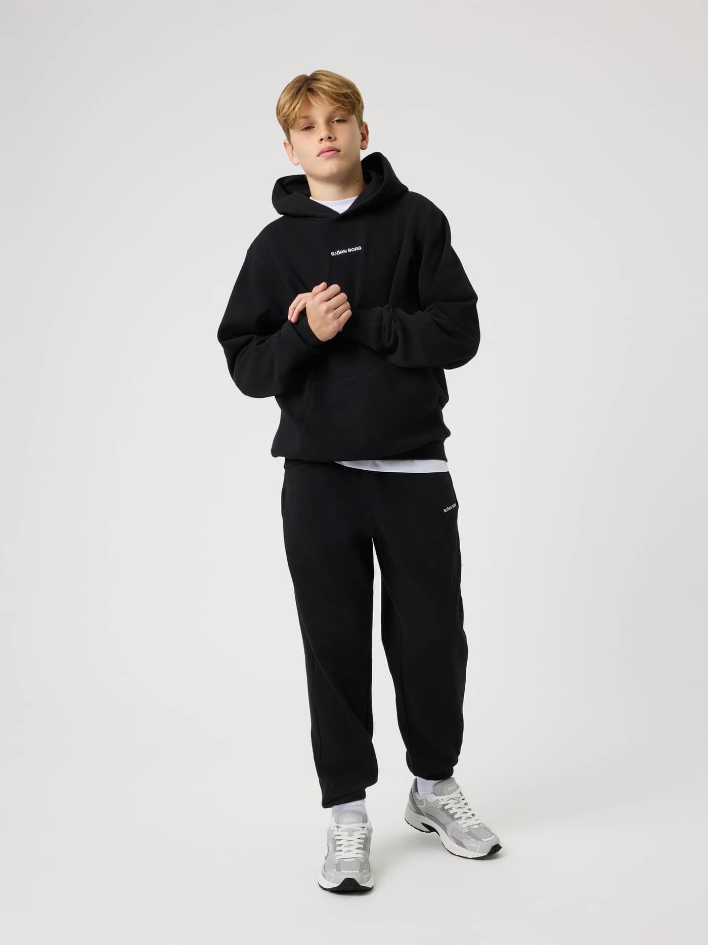 Front view of a model wearing the Borg Classic Hoodie in Black Beauty (Black) with a white logo for a kids training look. - Image 3