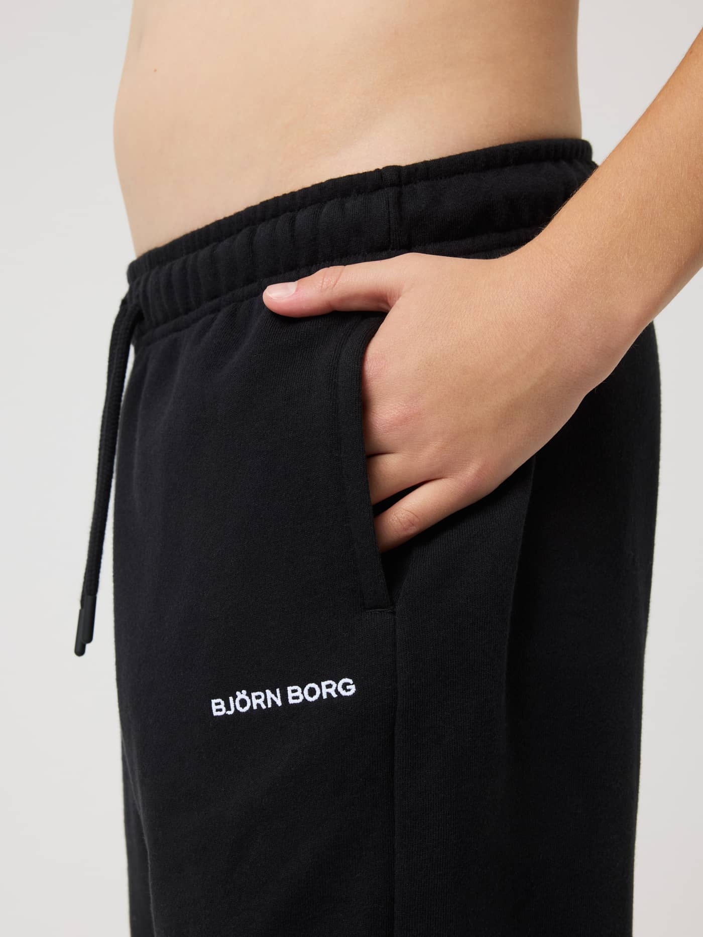 Side view of kids Borg Classic Sweatpants in Black Beauty (Black) with a side pocket and white logo embroidery. - Image 4