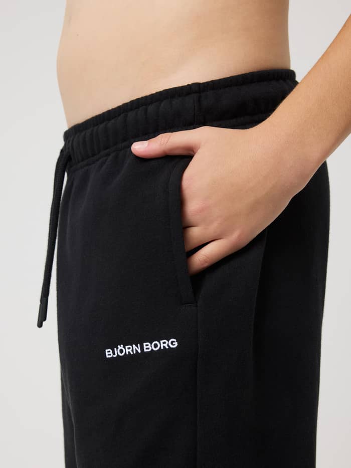 Side view of kids Borg Classic Sweatpants in Black Beauty (Black) with a side pocket and white logo embroidery. - Image 4