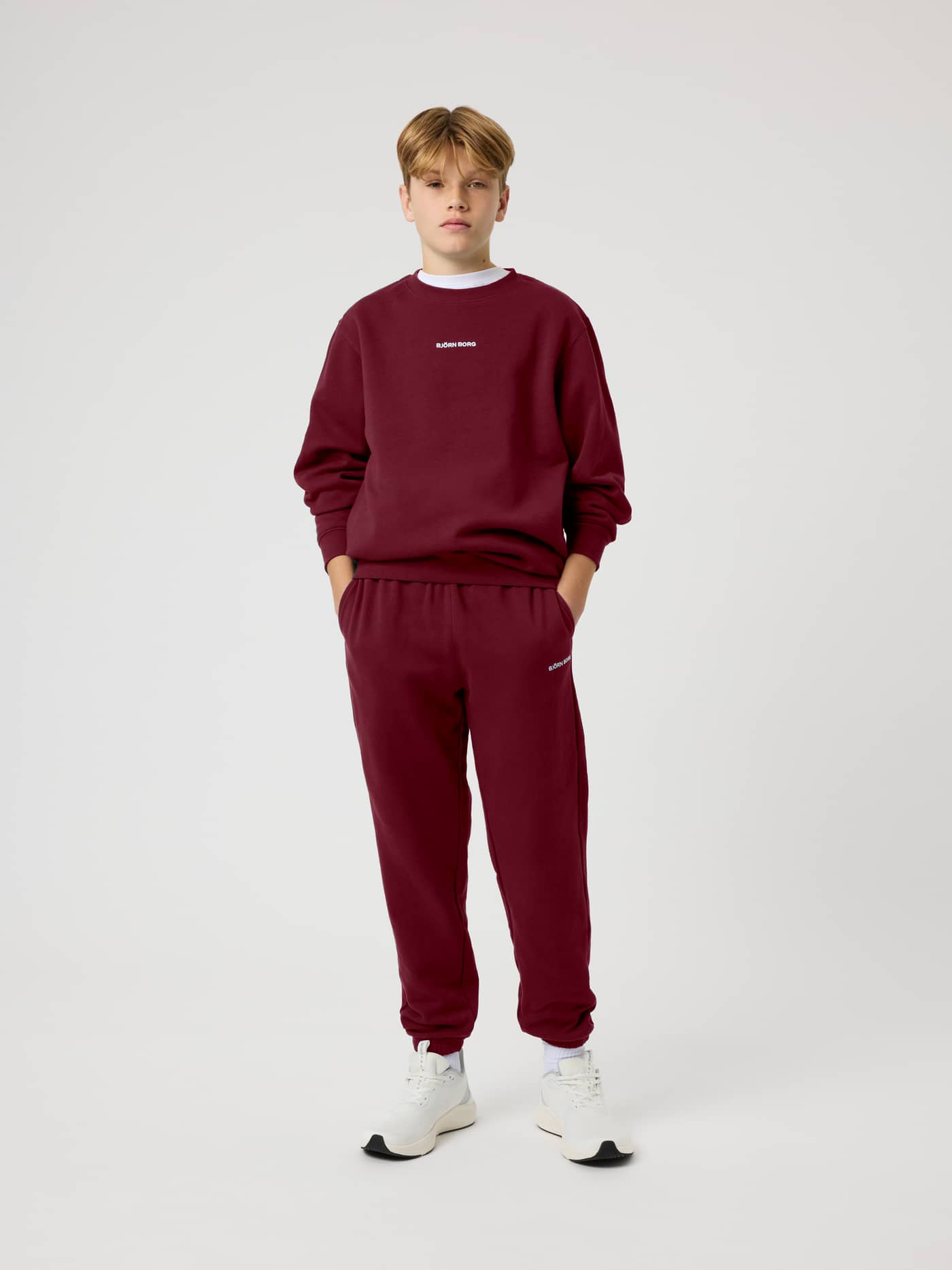 Front view of the Borg Classic Sweatpants in Cabernet (Red) on a kid, featuring side pockets and a relaxed fit. - Image 1