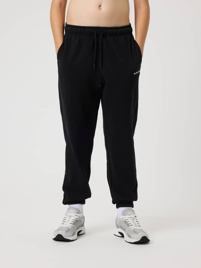 Front view of kids wearing Borg Classic Sweatpants in Black Beauty (Black) with a white logo and drawstring waist.