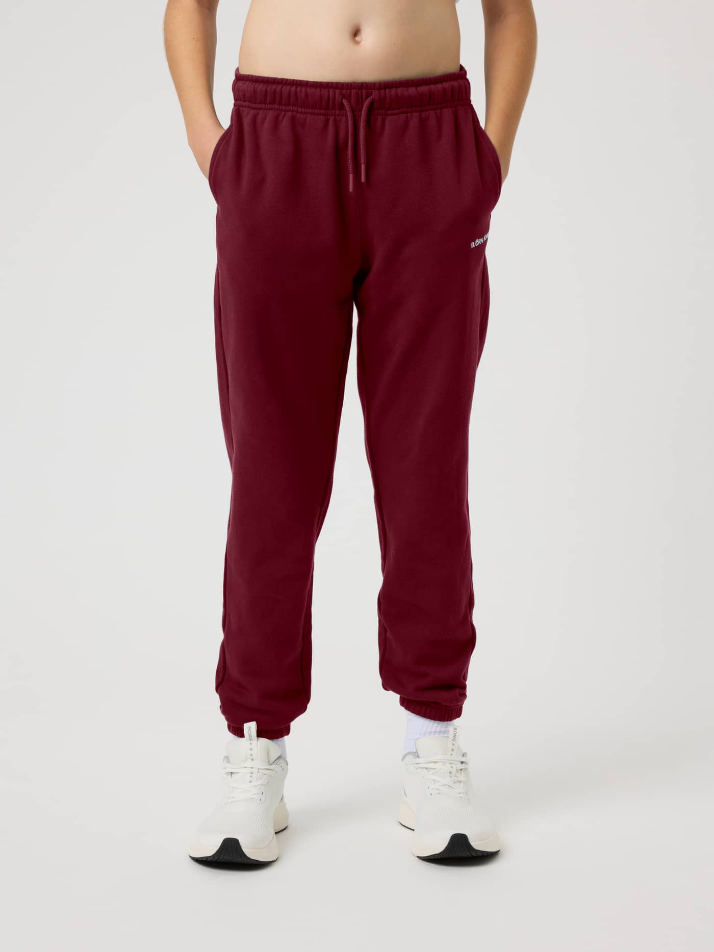 Front view of the Borg Classic Sweatpants in Cabernet (red) on a kid with an adjustable drawstring waist and side pockets. - Image 2