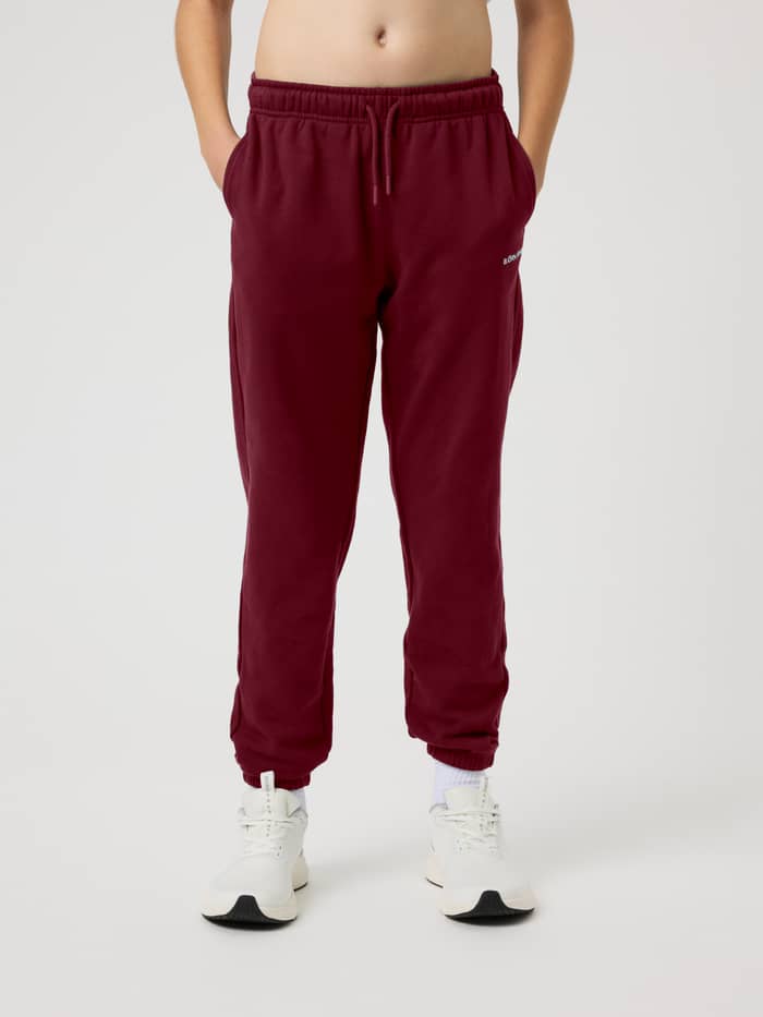 Front view of the Borg Classic Sweatpants in Cabernet (red) on a kid with an adjustable drawstring waist and side pockets.