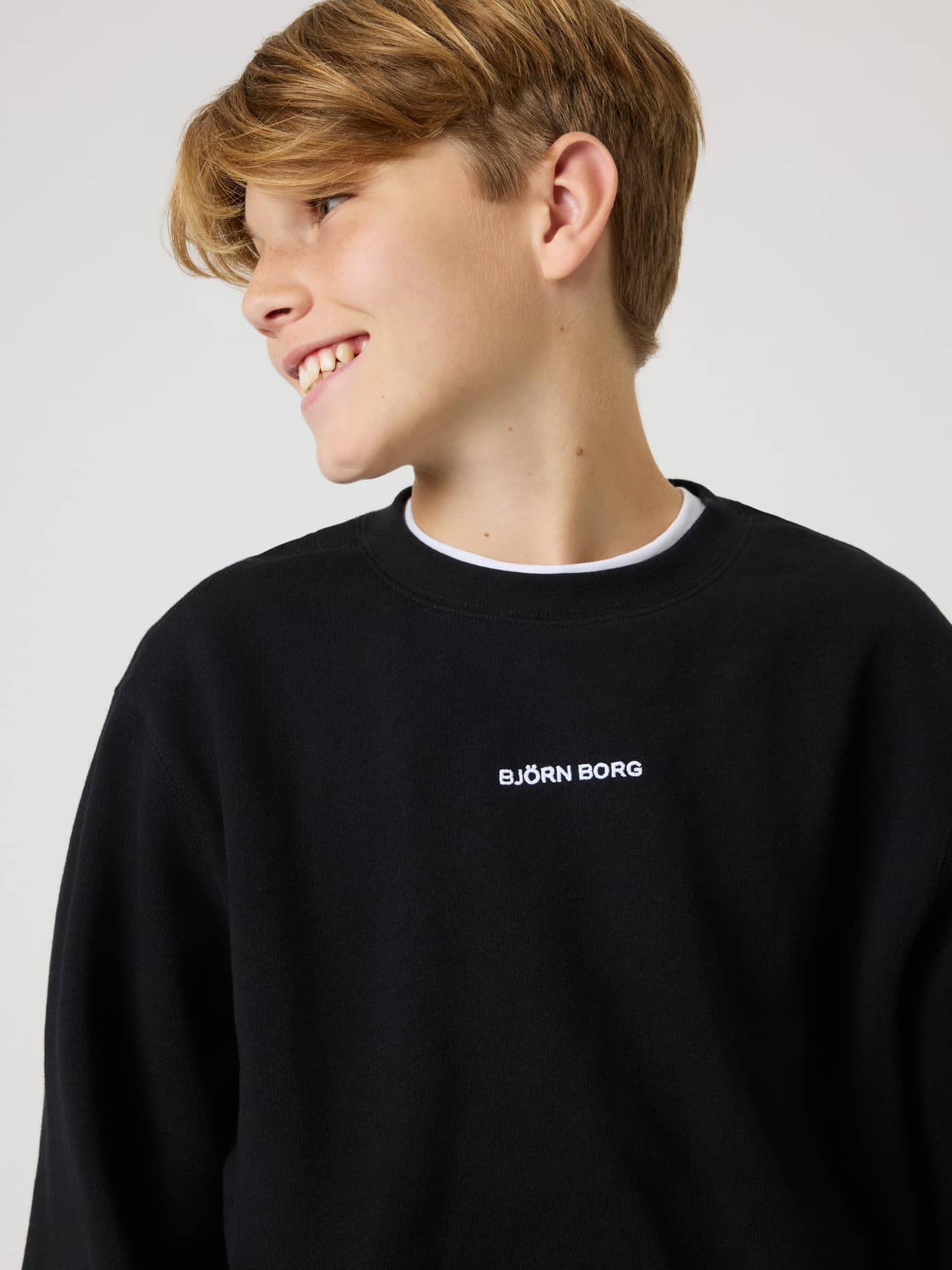Close-up of the kids Borg Classic Sweatshirt in Black Beauty (Black) featuring white logo embroidery for tennis. - Image 4