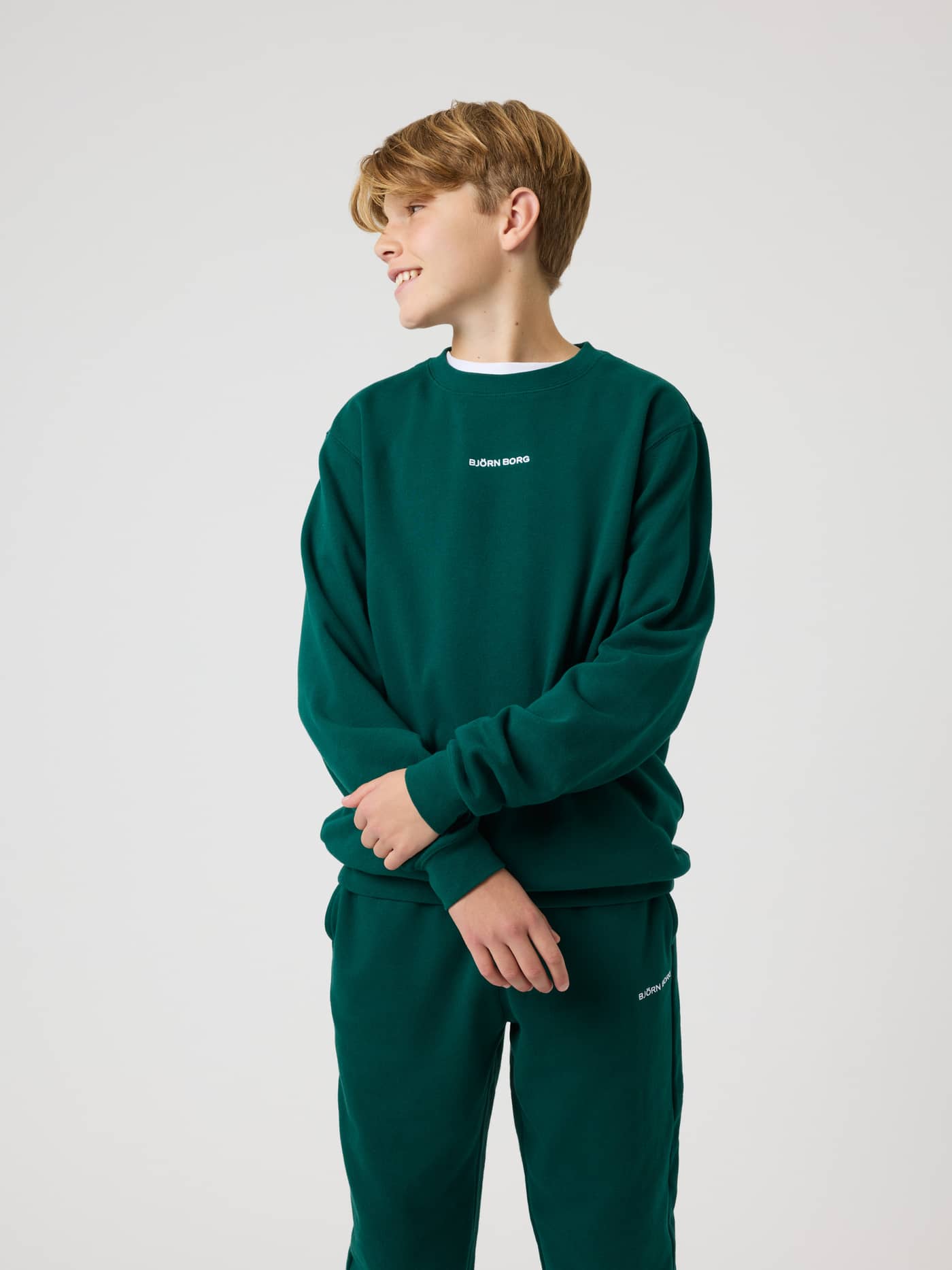 Front view of a kid wearing the kids' Borg Classic Sweatshirt in Rain Forest (Green) with a white embroidered chest logo. - Image 1