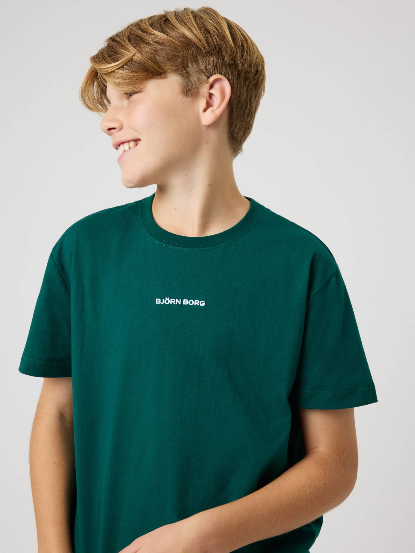 Front view of a boy wearing the kids Borg Classic T-Shirt in Rain Forest (Green) with a white logo, perfect for tennis. - Image 5