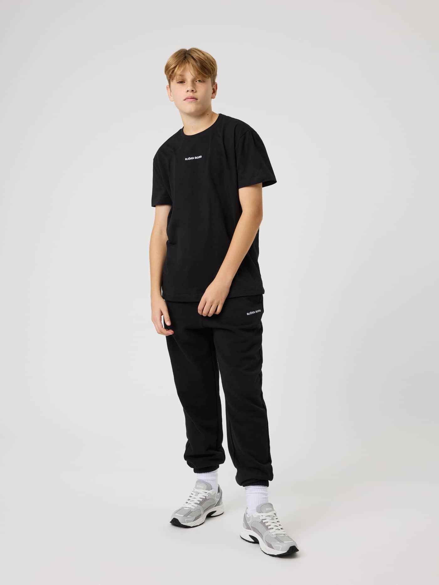 Full-body view of a boy in the kids cotton Borg Classic T-Shirt in Black Beauty (Black) with white embroidery for tennis. - Image 3