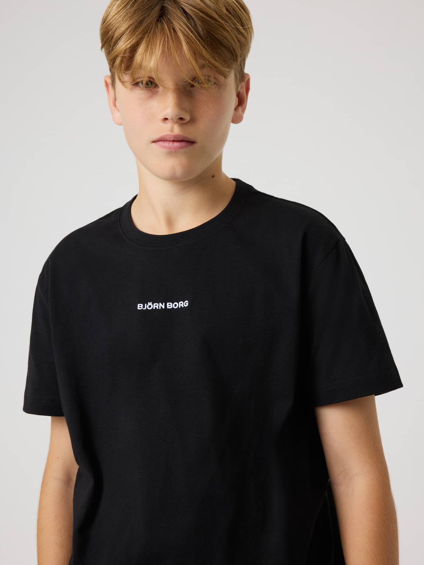Front close-up of a kid wearing the Borg Classic T-Shirt in Black Beauty (Black) with white logo embroidery. - Image 4