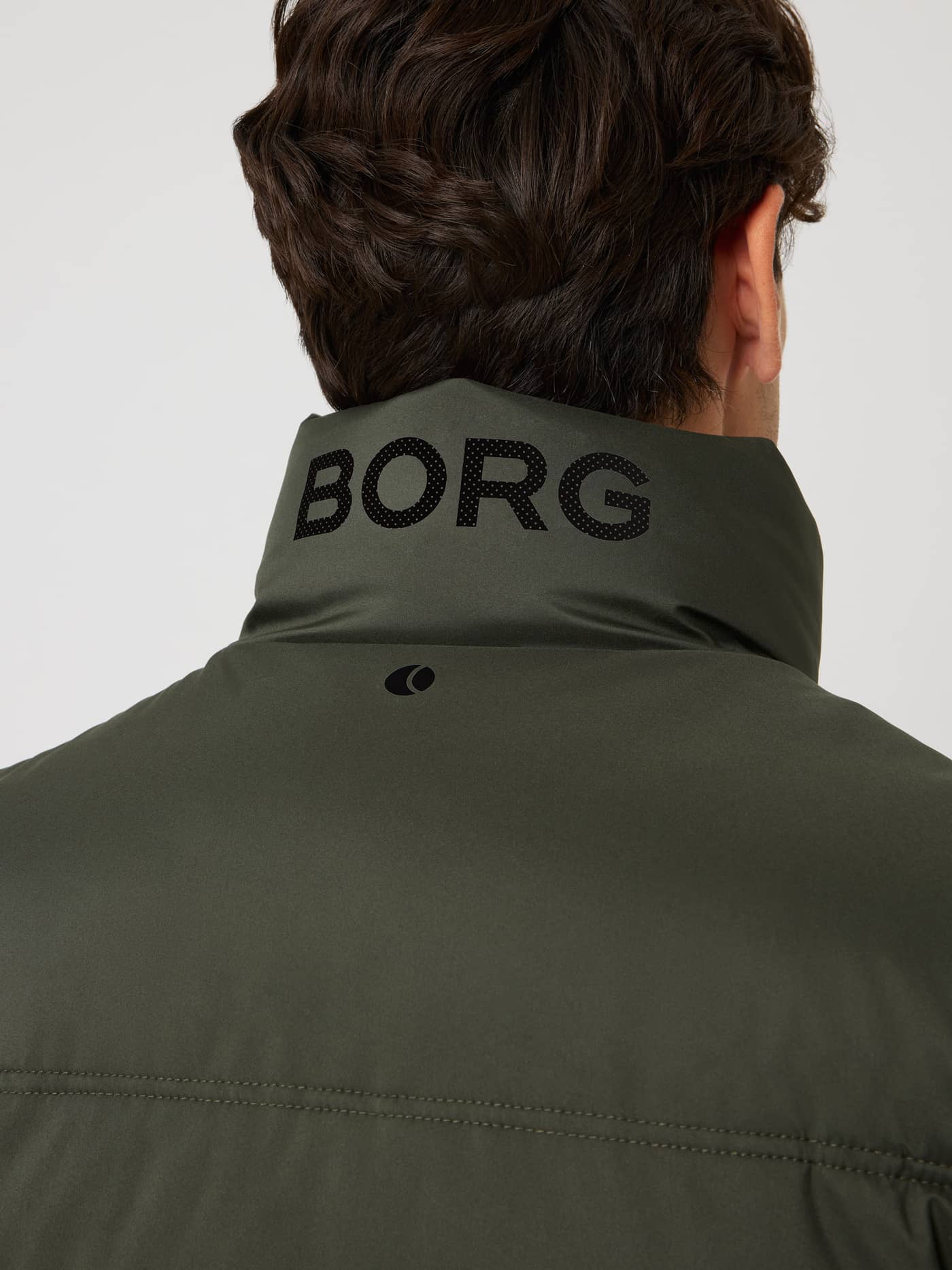 Kragen på Borg Puffer Jacket i Rosin (Grønn) med svart perforert logo og tennisballprint for trening og tennis. - Image 4