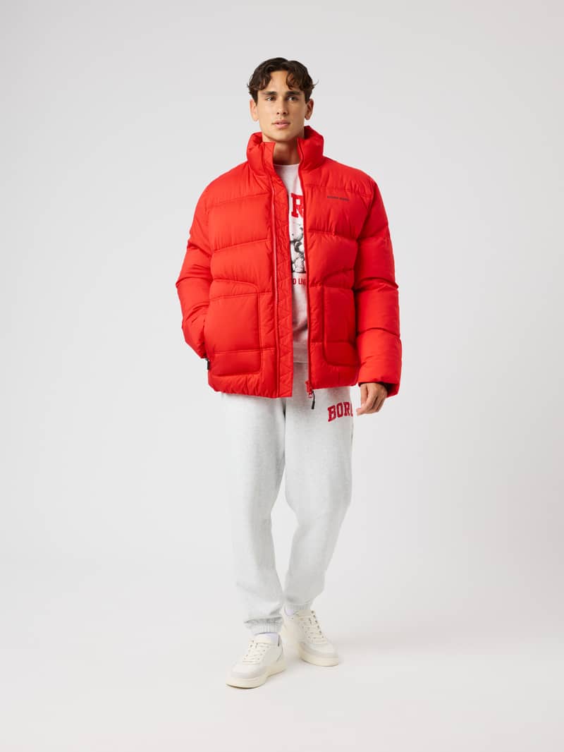 Front view of a model wearing the Borg Puffer Jacket in Flame Scarlet (Red) with a black logo for training. - Image 3