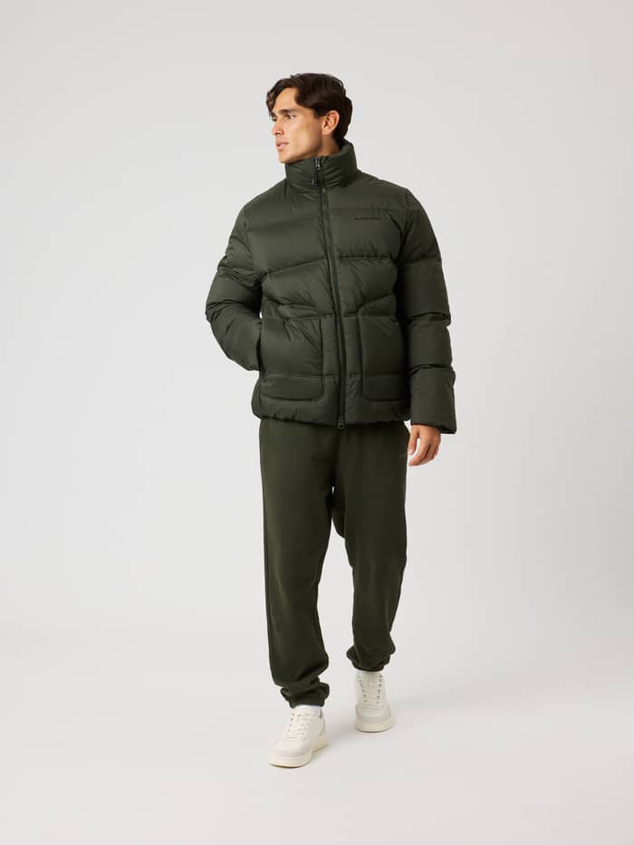 Front view of a model wearing the padded Borg Puffer Jacket in Rosin (Green) with a black logo, for training movement. - Image 3