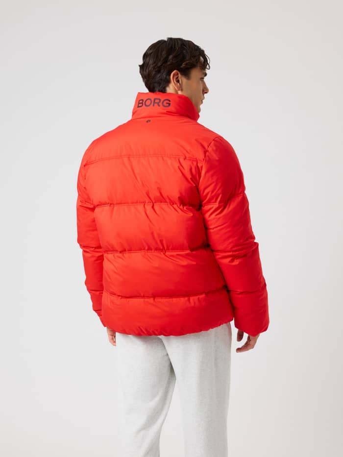 Back view of a man wearing the Borg Puffer Jacket in Flame Scarlet (Red) with a padded design and logo for training. - Image 2