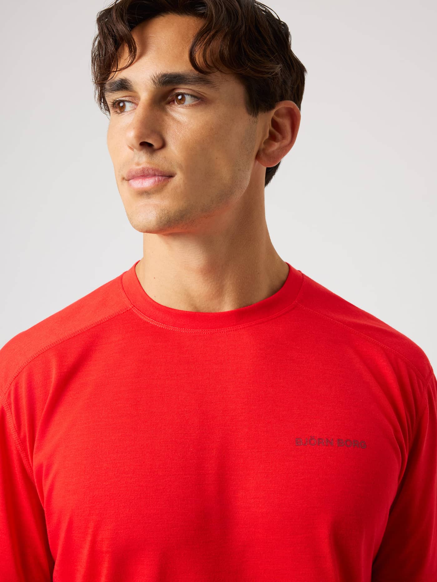 Close-up of the Borg Soft Sports T-Shirt in Flame Scarlet (Red) for training and tennis with a grey chest logo. - Image 5