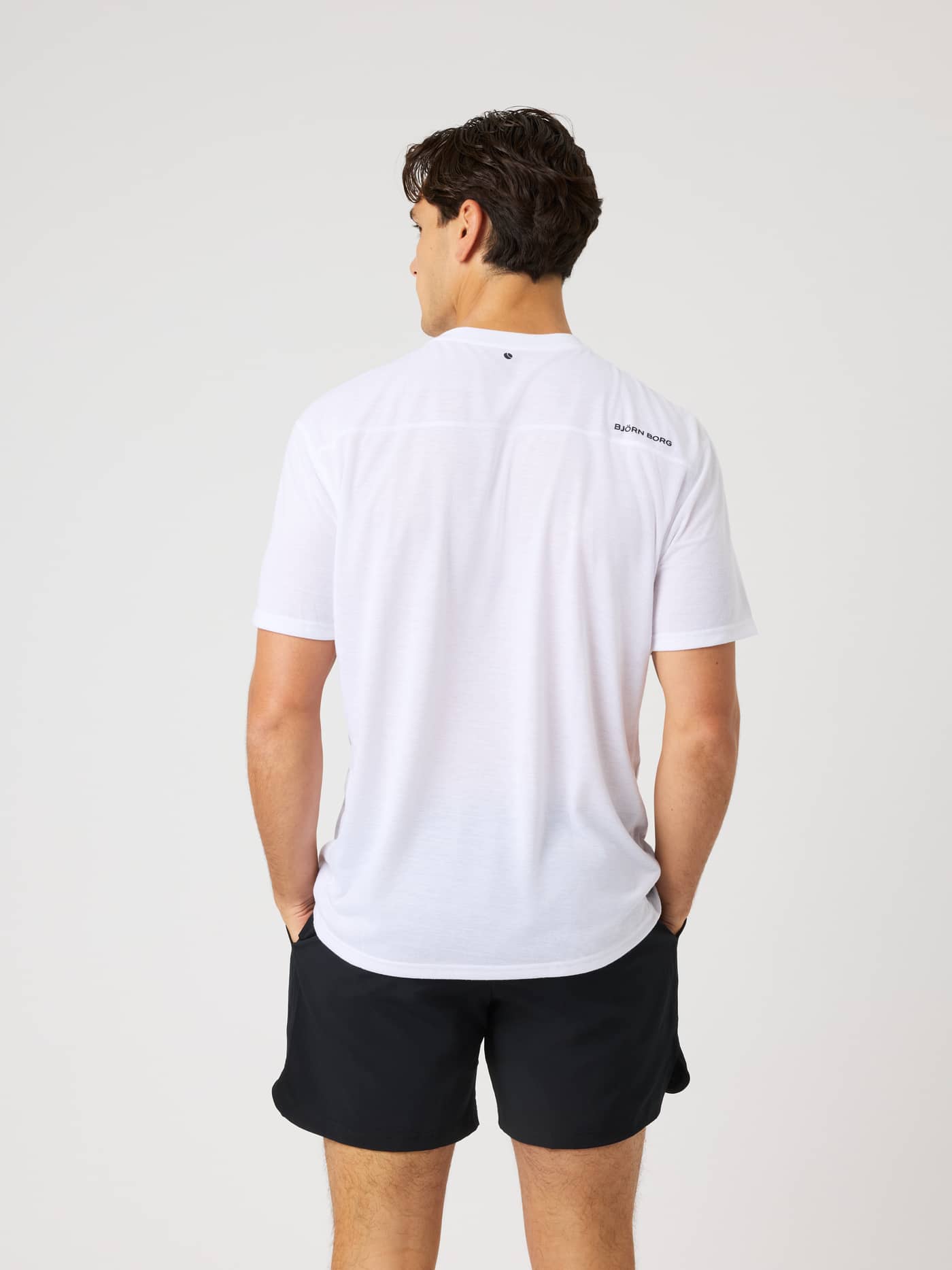Back view of a man in the Borg Soft Sports T-Shirt in Brilliant White (White) with a black logo for training or tennis. - Image 2
