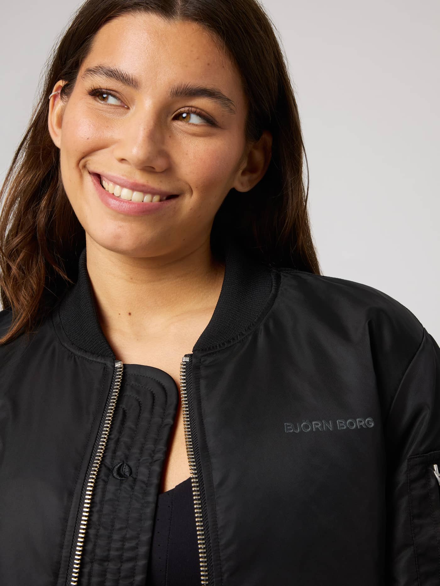 Nærbilde av Studio Bomber Jacket i Black Beauty (Svart) med tonal logo og ribbestrikket krage. - Image 4