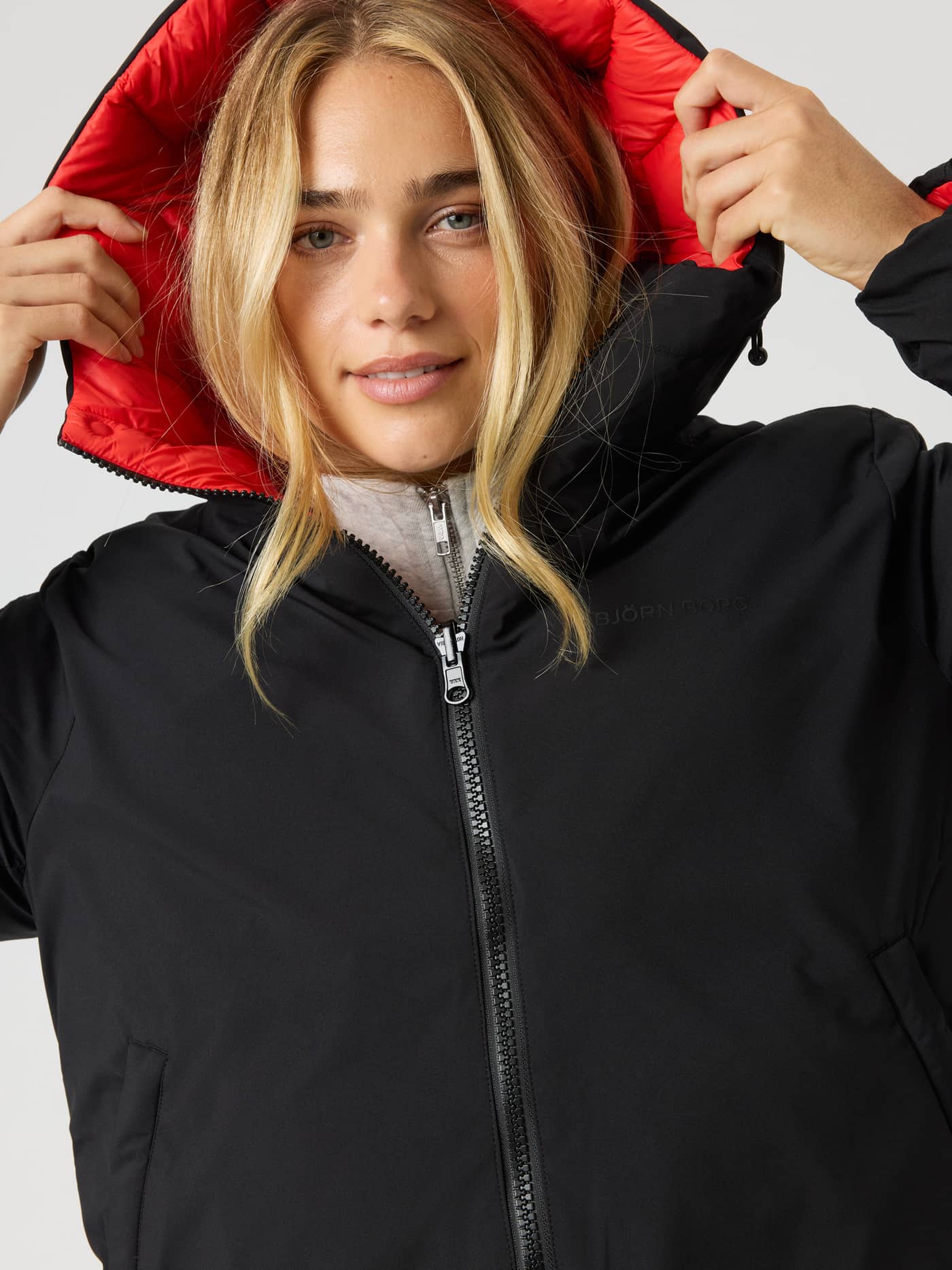 Nærbilde av Studio Reversible Puffer Jacket i Black Beauty (Svart) med rød hette og tonal logo på brystet. - Image 4
