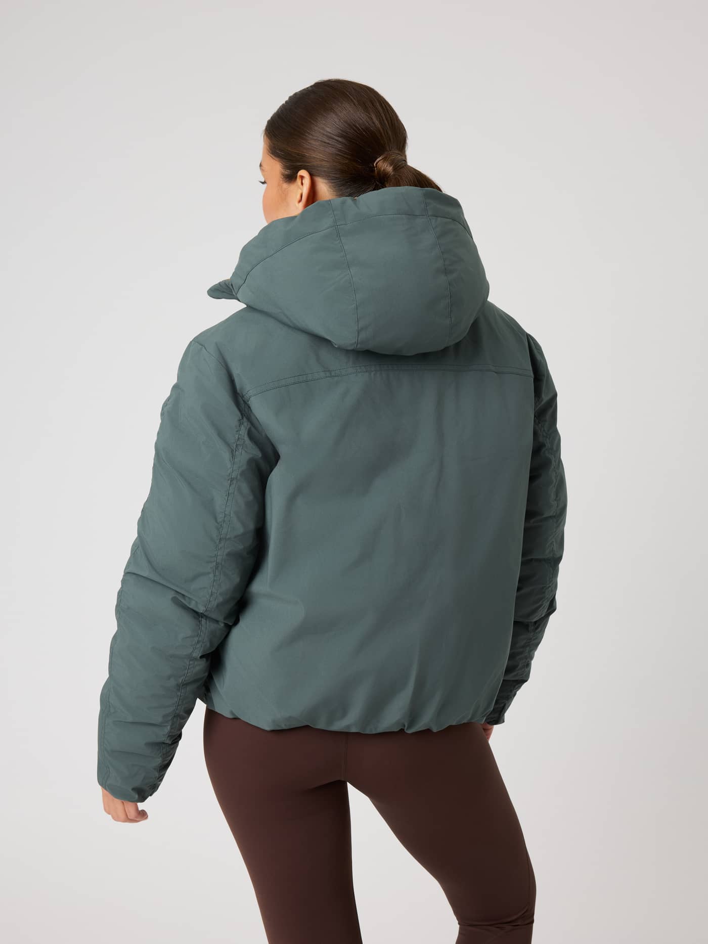 Studio Reversible Puffer Jacket i Urban Chic (Grønn) sett bakfra på modell, med vattert design og hette. - Image 4