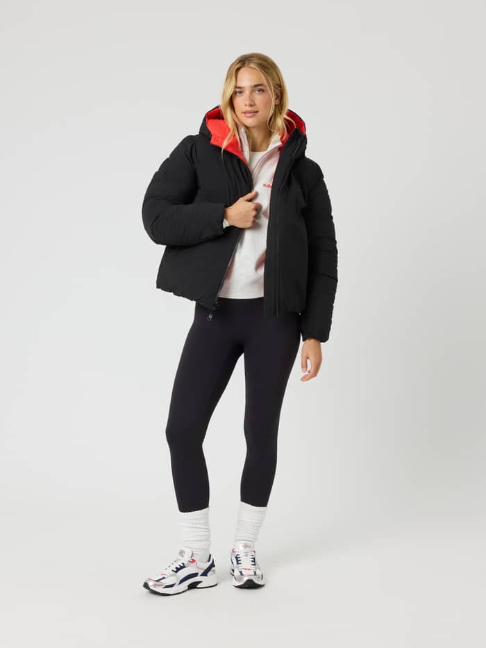 Vue de face d'une femme portant la Studio Reversible Puffer Jacket matelassée en Black Beauty (Noir) à doublure rouge. - Image 3