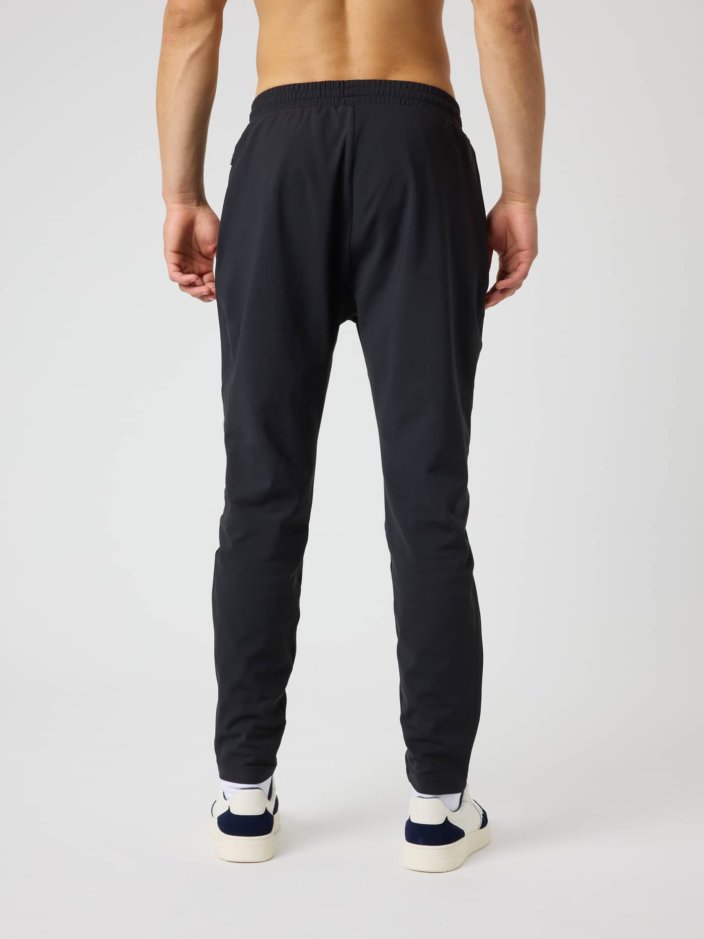 Back view of a model wearing Ace Court Pants in Black Beauty (Black) for functional tennis training. - Image 2