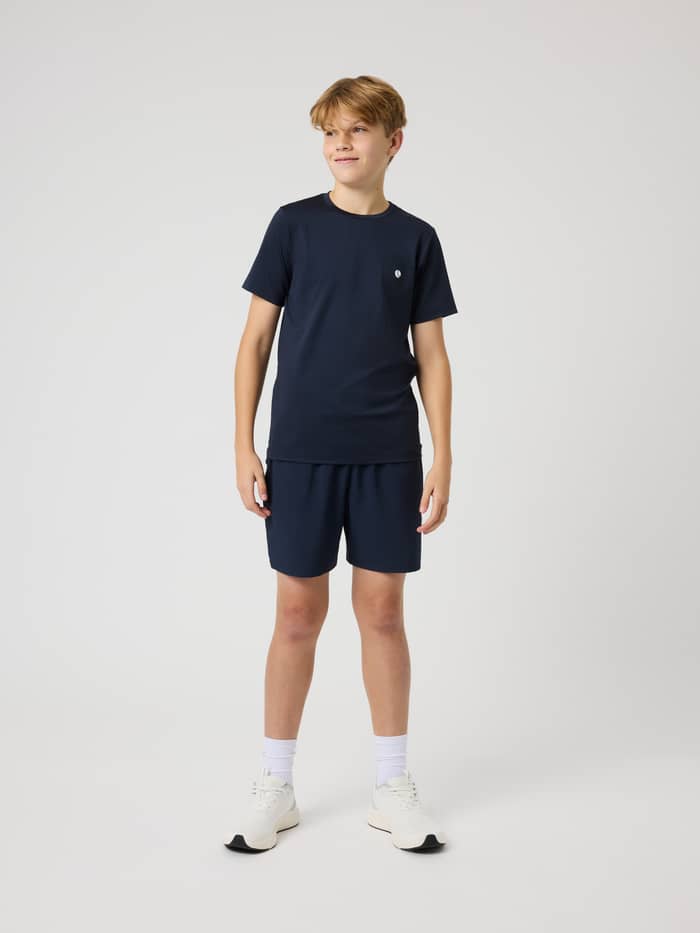 Ace Slim T-Shirt i Night Sky (Marineblå) set i helfigur på en dreng, en kids tennistop med lille hvidt logo til tennis. - Image 4
