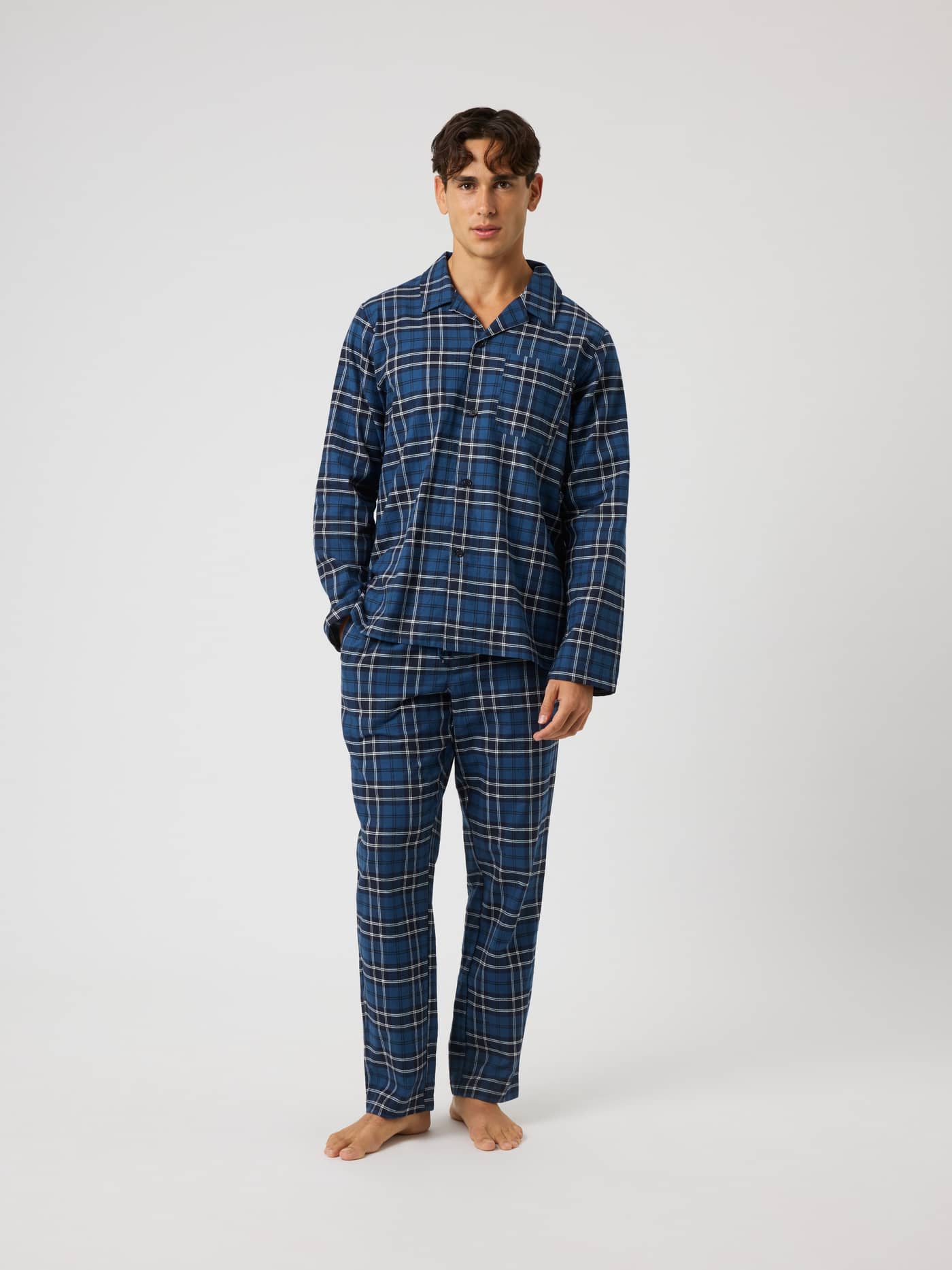 Full-body front view of a man wearing the Core Flannel Pyjama Shirt in a blue and navy BB Forest Tartan 4 plaid pattern. - Image 3