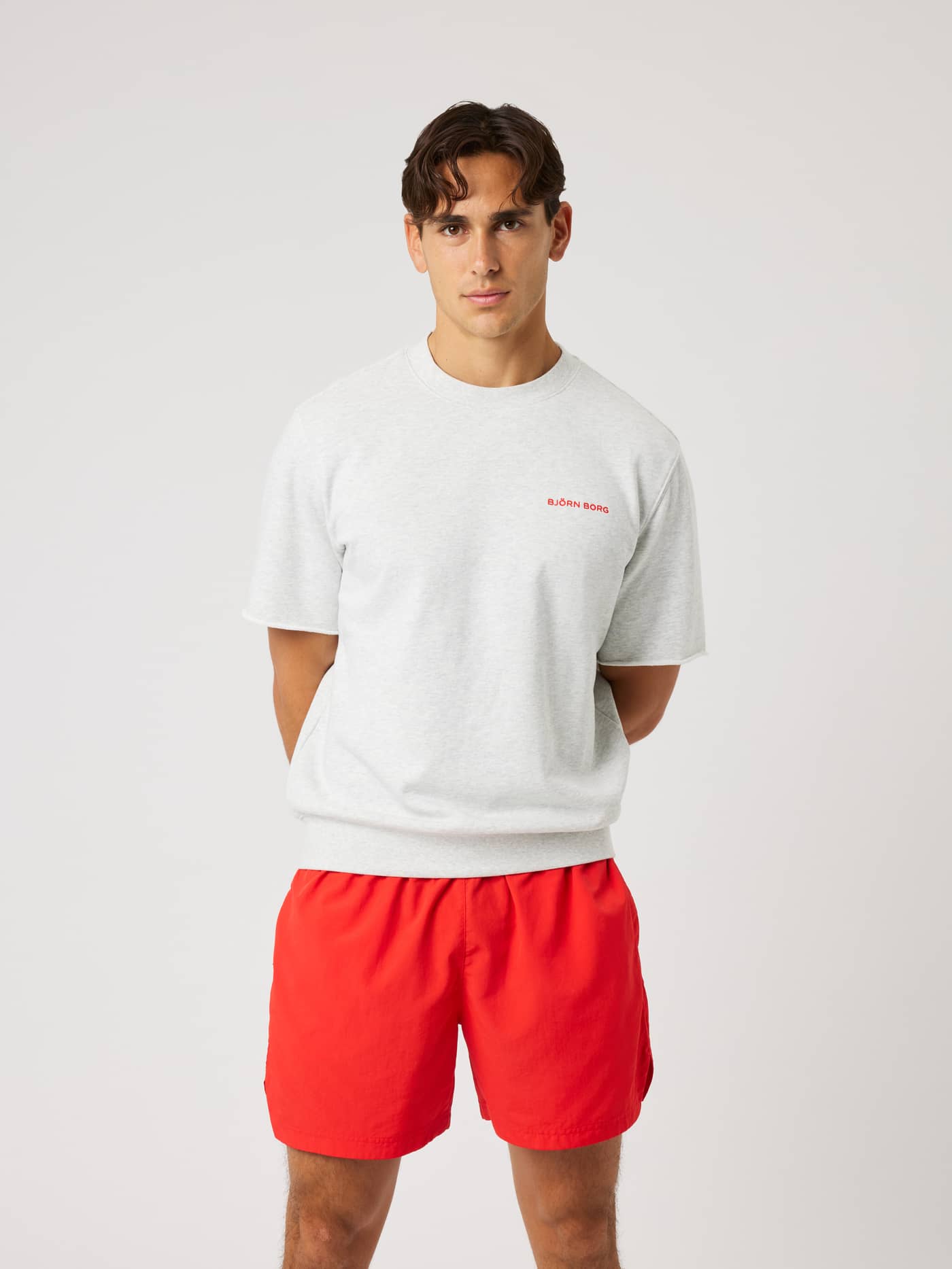 Model in the Borg Oversized Short Sleeve Sweatshirt in Ultra Light Grey Melange (Grey) with a red logo for training. - Image 2