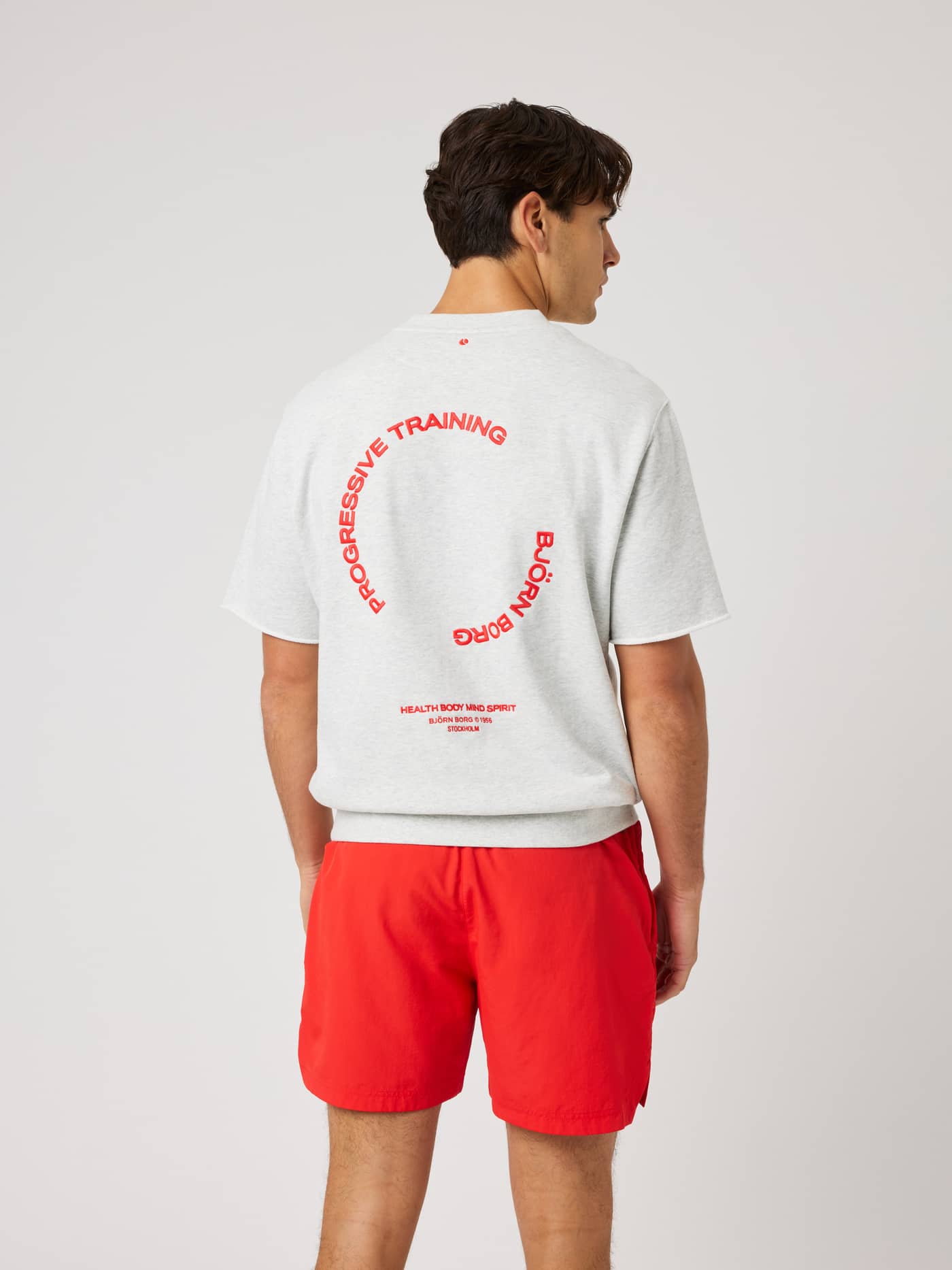 Back view of the Borg Oversized Short Sleeve Sweatshirt in Ultra Light Grey Melange (Grey) with red training graphics. - Image 3