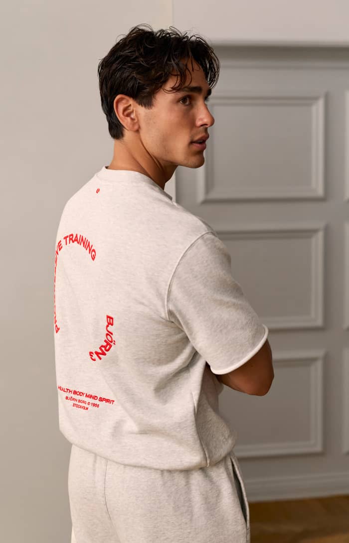 Rückansicht des Borg Oversized Short Sleeve Sweatshirt in Ultra Light Grey Melange (Grau) mit roter Trainingsgrafik.
