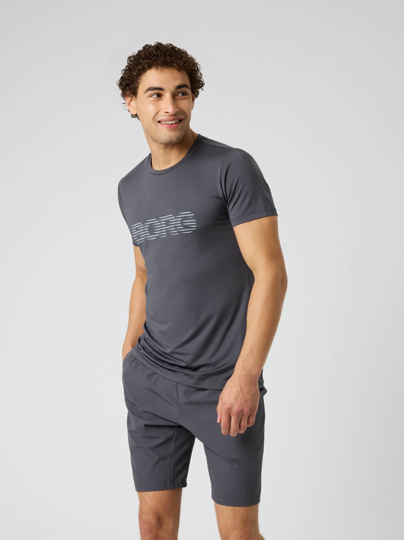 Vue de face d'un modèle en Borg Graphic T-Shirt Asphalt (Gris), un haut de training fonctionnel avec logo blanc. - Image 1
