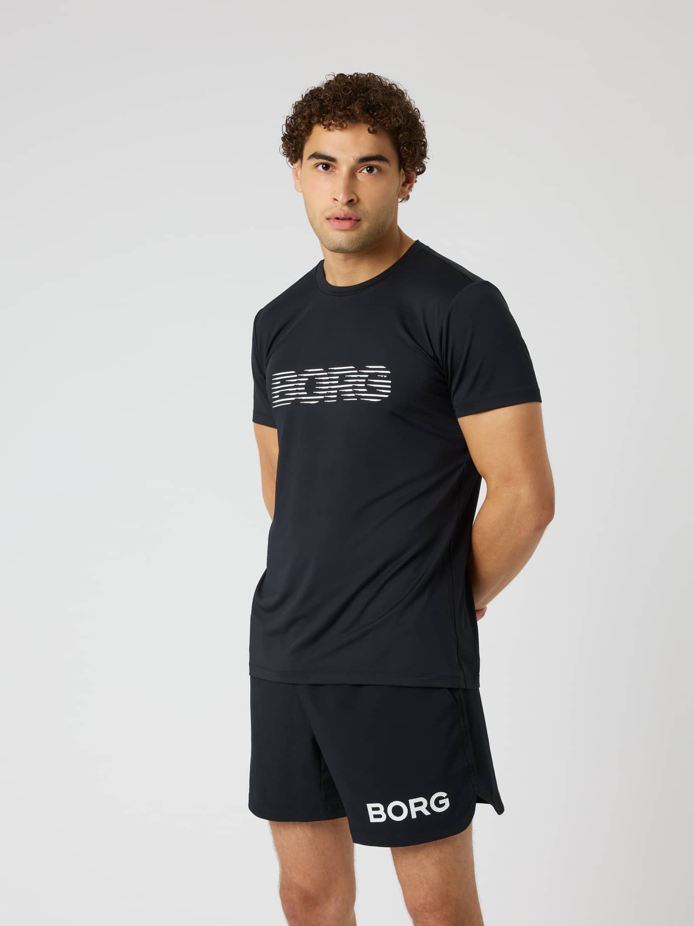 Vue de face d'un modèle en Borg Graphic T-Shirt en Black Beauty (Noir) avec un logo blanc pour le training. - Image 1