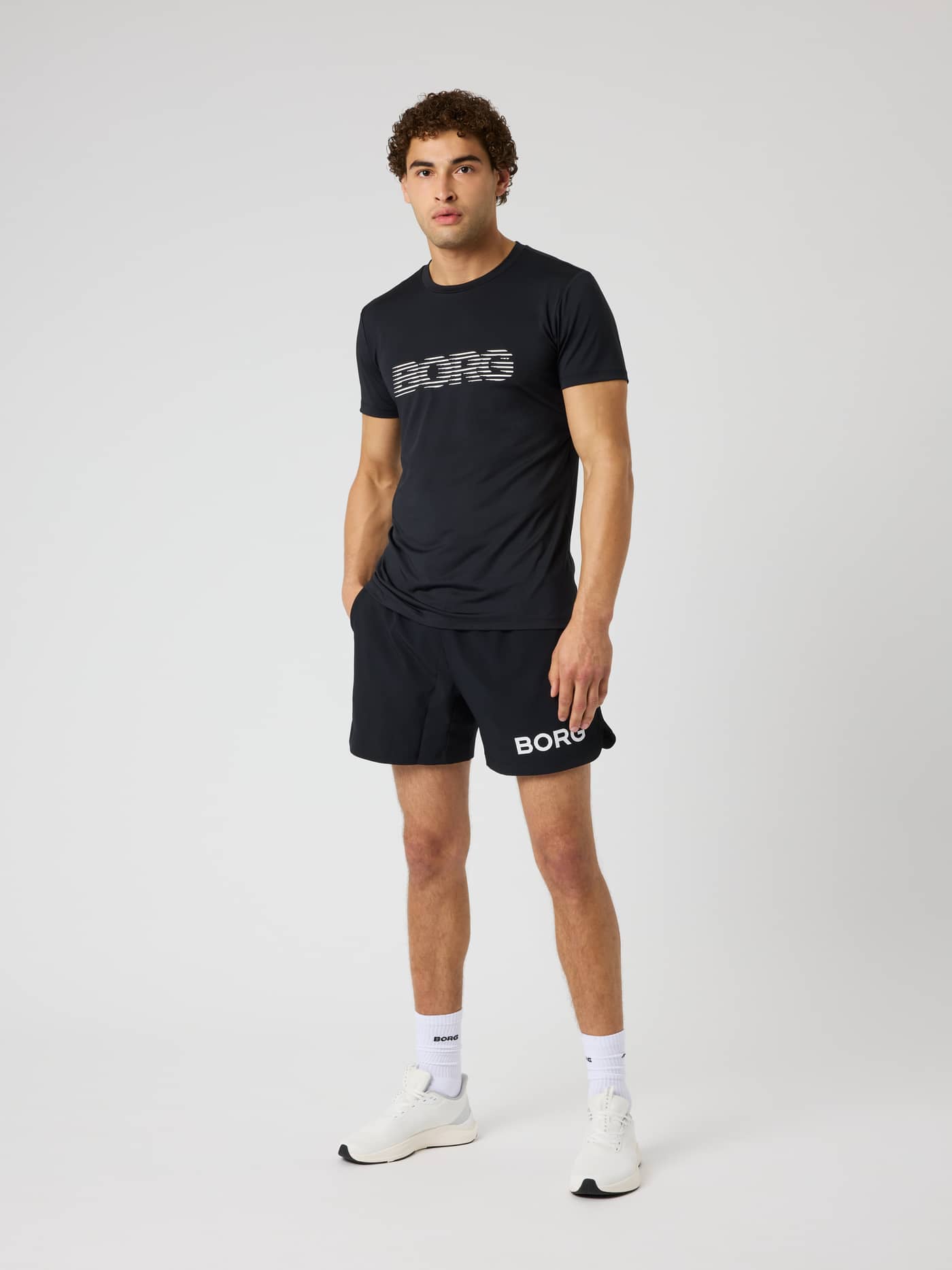 Full-body view of a model wearing the Borg Graphic T-Shirt in Black Beauty (Black) with a white chest logo for training. - Image 4