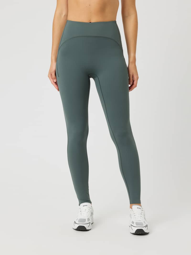 Front view of a model wearing Borg Reform Pocket Tights in Urban Chic (Green) for high-waisted training comfort.