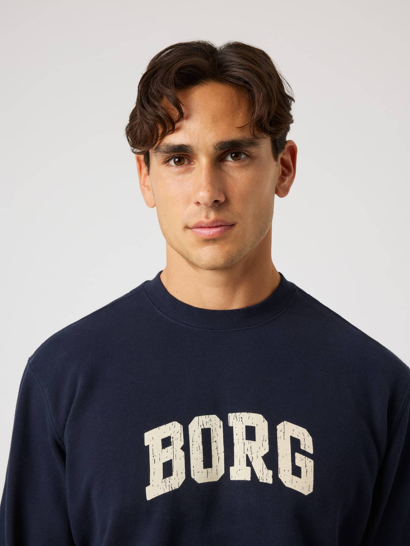Portrait of a model wearing the Borg Classic Print Sweatshirt in Night Sky (Navy) with a white chest logo for tennis. - Image 5