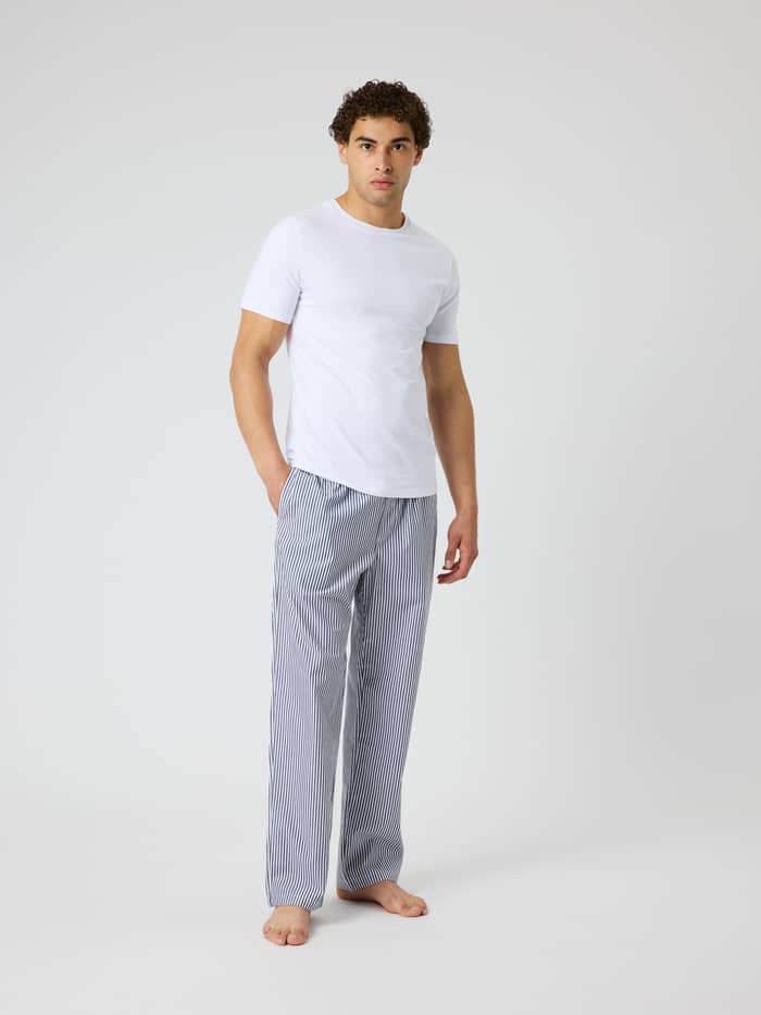 Vorderansicht eines Mannes in Core Woven Logo Pyjama Pants in BB Fresh Stripe 5 (Blau) mit klassischem Streifenmuster. - Image 3