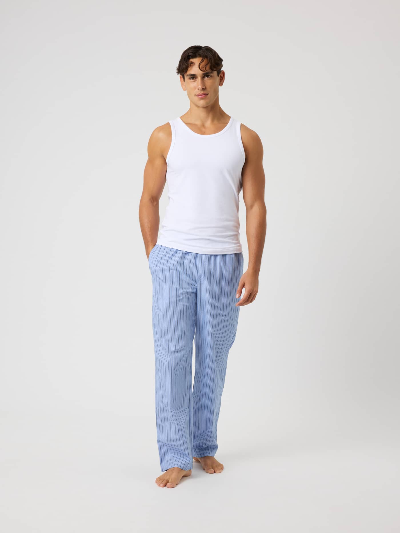 Full-body front view of a man wearing Core Woven Logo Pyjama Pants in Tripple Lw Stripe 2 (Blue) with vertical stripes. - Image 3