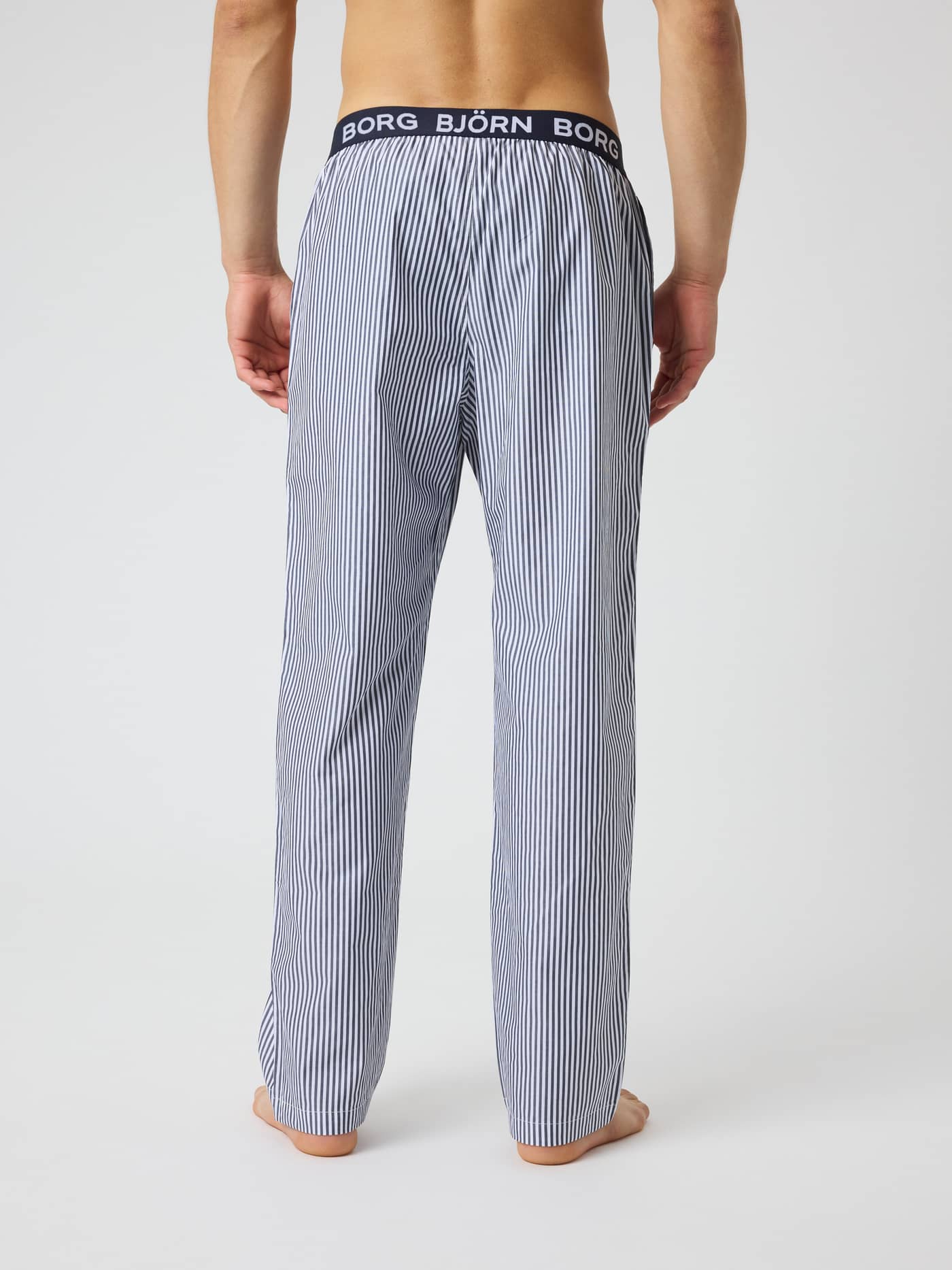 Back view of Core Woven Logo Pyjama Pants in Fresh Stripe 5 (Blue) with a striped pattern and white logo waistband. - Image 2