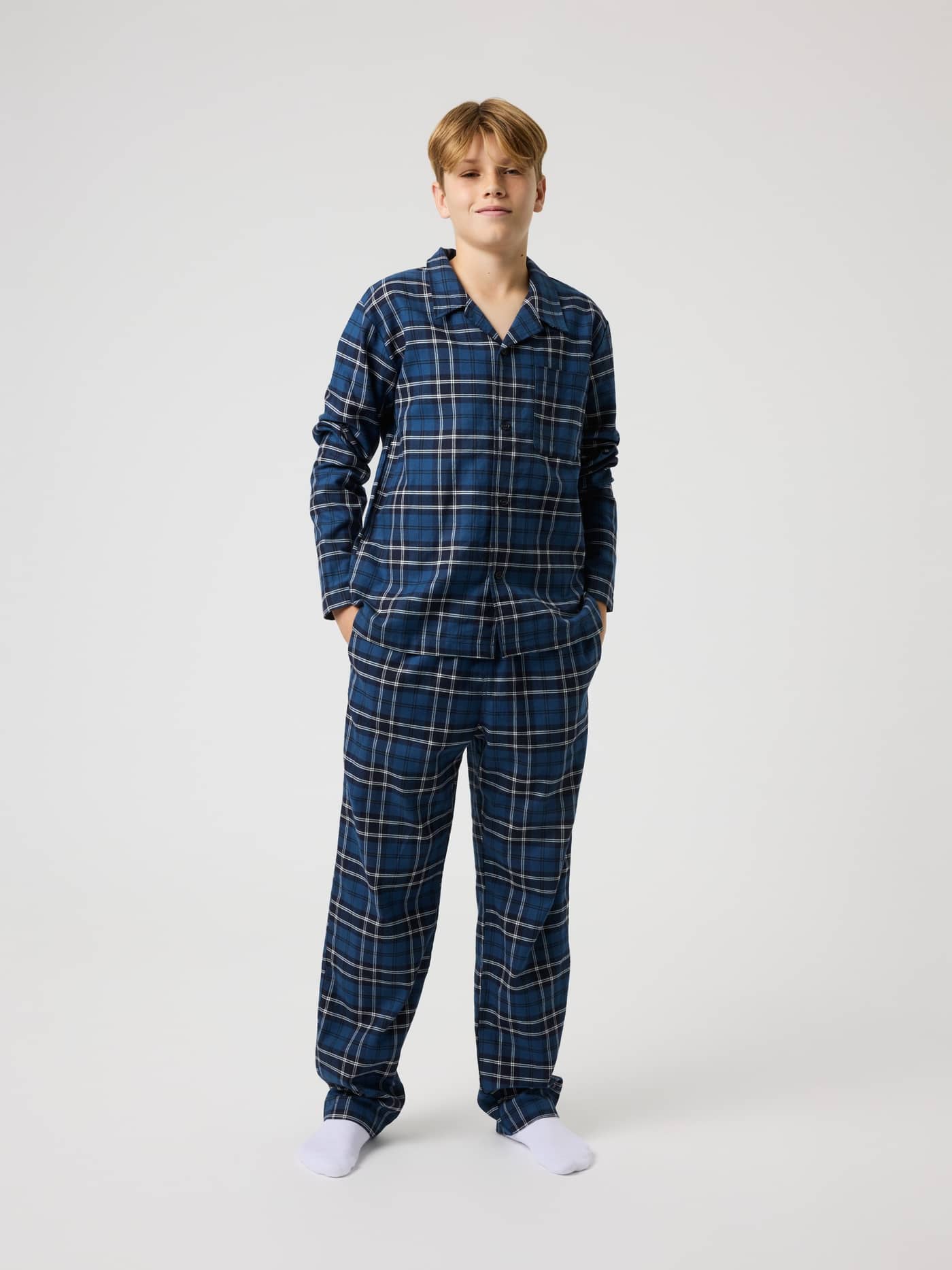 Full-body view of a kid wearing the Core Flannel Pyjama Shirt in Forest Tartan 4 (Blue) with a classic tartan pattern. - Image 2