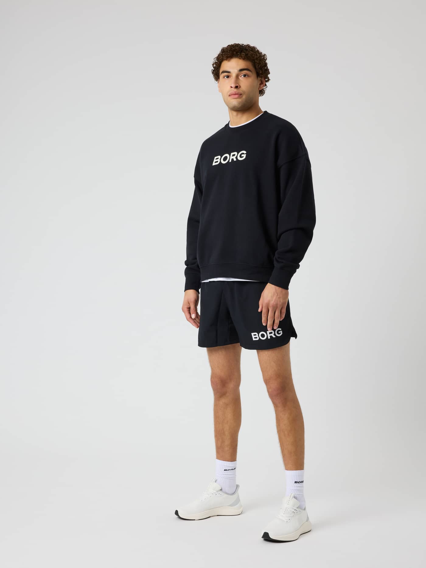 Full-body view of a model wearing the Borg Oversized Sweatshirt in Black Beauty (Black) with a white logo for training. - Image 4