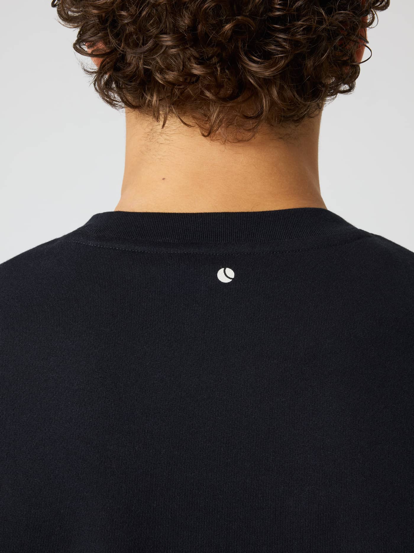 Back neck detail of the Borg Oversized Sweatshirt in Black Beauty (Black) with a white tennis ball print for training. - Image 5