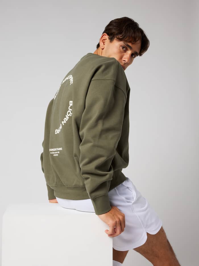 Back view of a man wearing the Borg Oversized Sweatshirt in Kalamata (Green) with a tennis-inspired print for training.