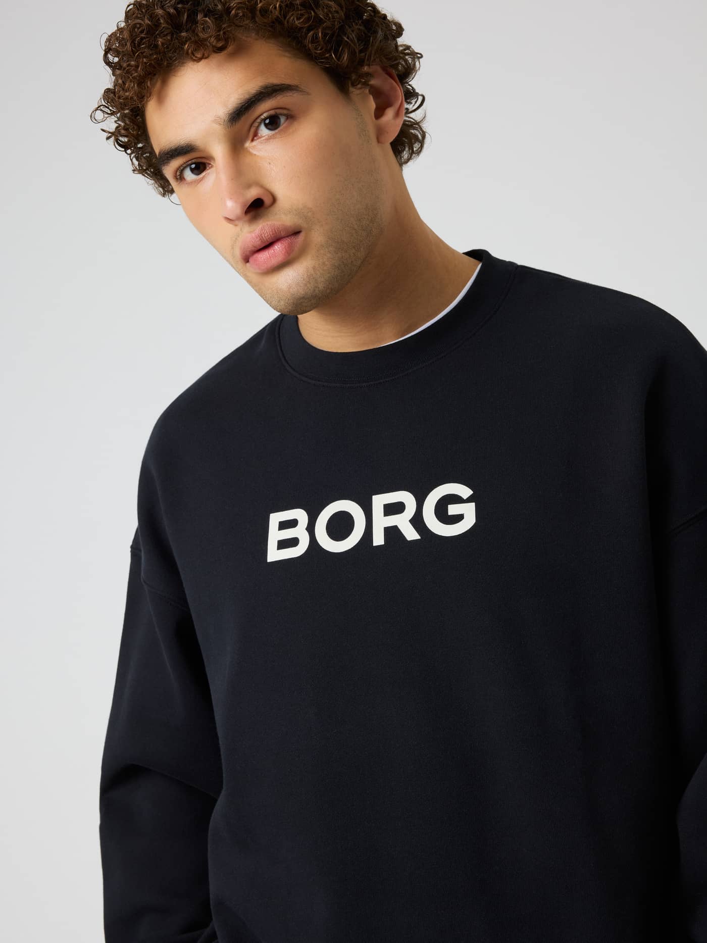Model in the Borg Oversized Sweatshirt in Black Beauty (Black), a training and tennis layer with a white chest logo. - Image 6