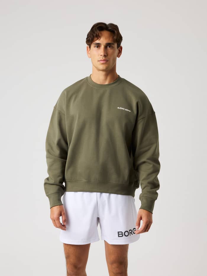 Vorderansicht eines Models im Borg Oversized Sweatshirt in Kalamata (Grün) mit weißem Logo zum Training.