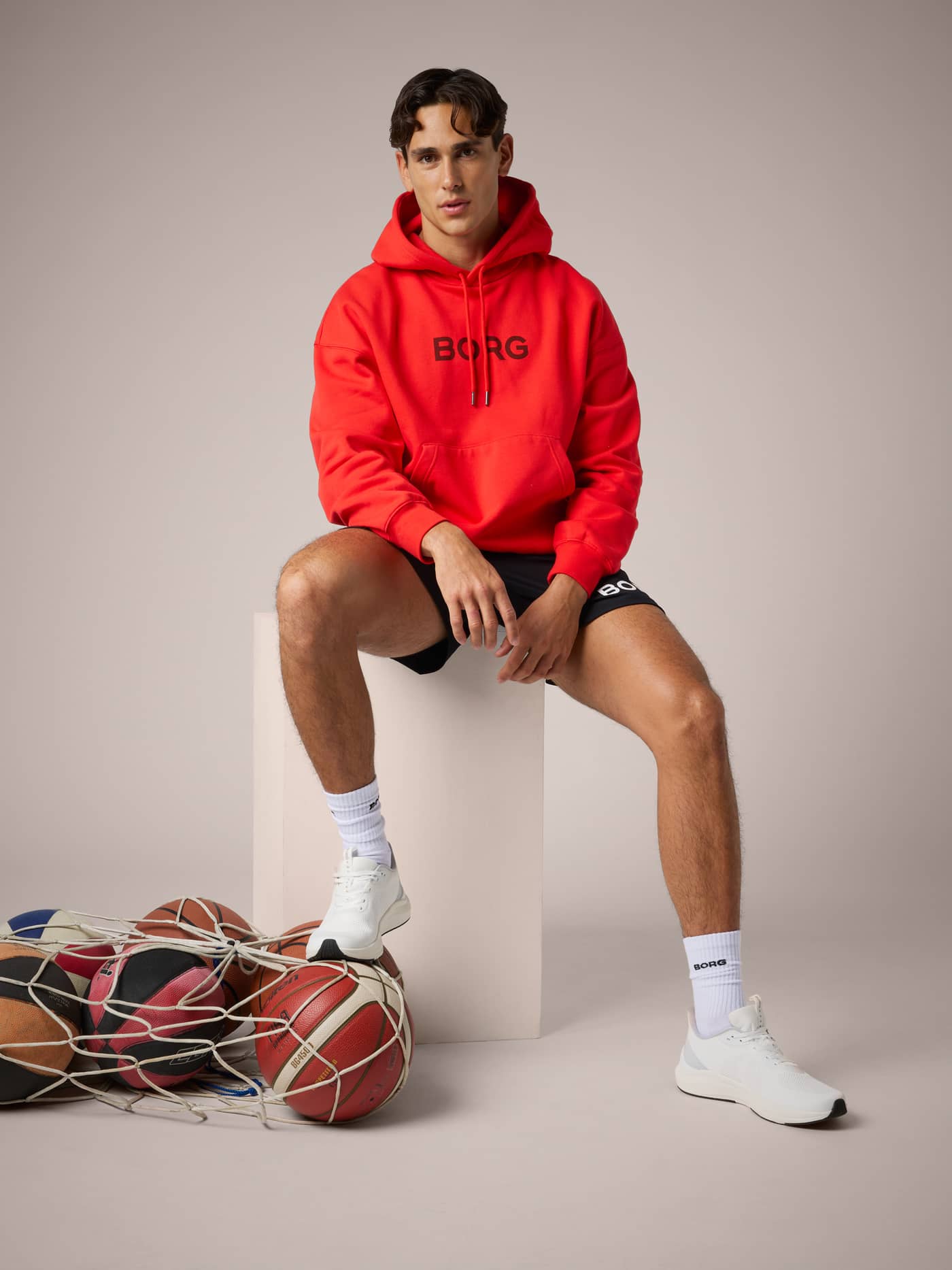 Front view of a model wearing the Borg Oversized Hoodie in Flame Scarlet (Red) featuring a black logo for training. - Image 6